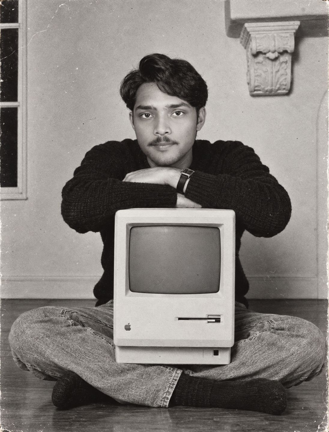 Suyash Pandey in a black-and-white portrait with a vintage Macintosh computer